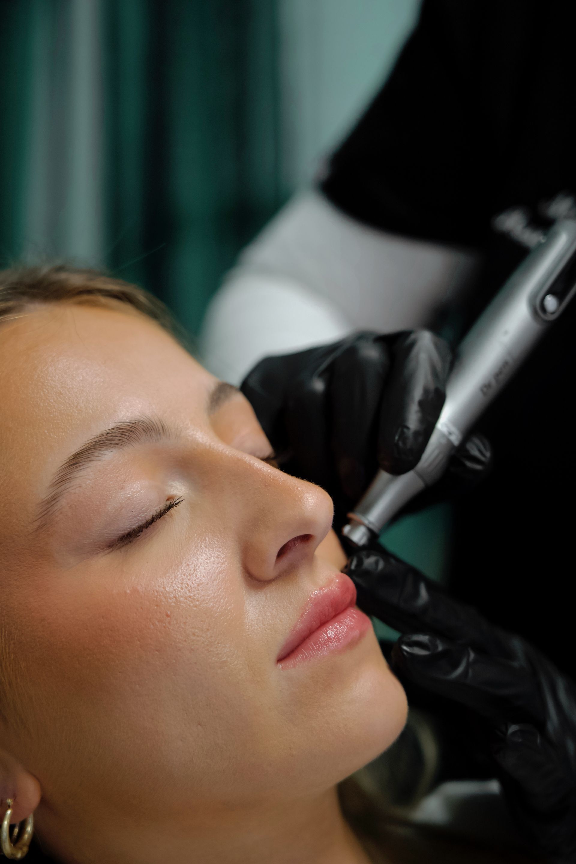A woman is getting a tattoo on her lip.