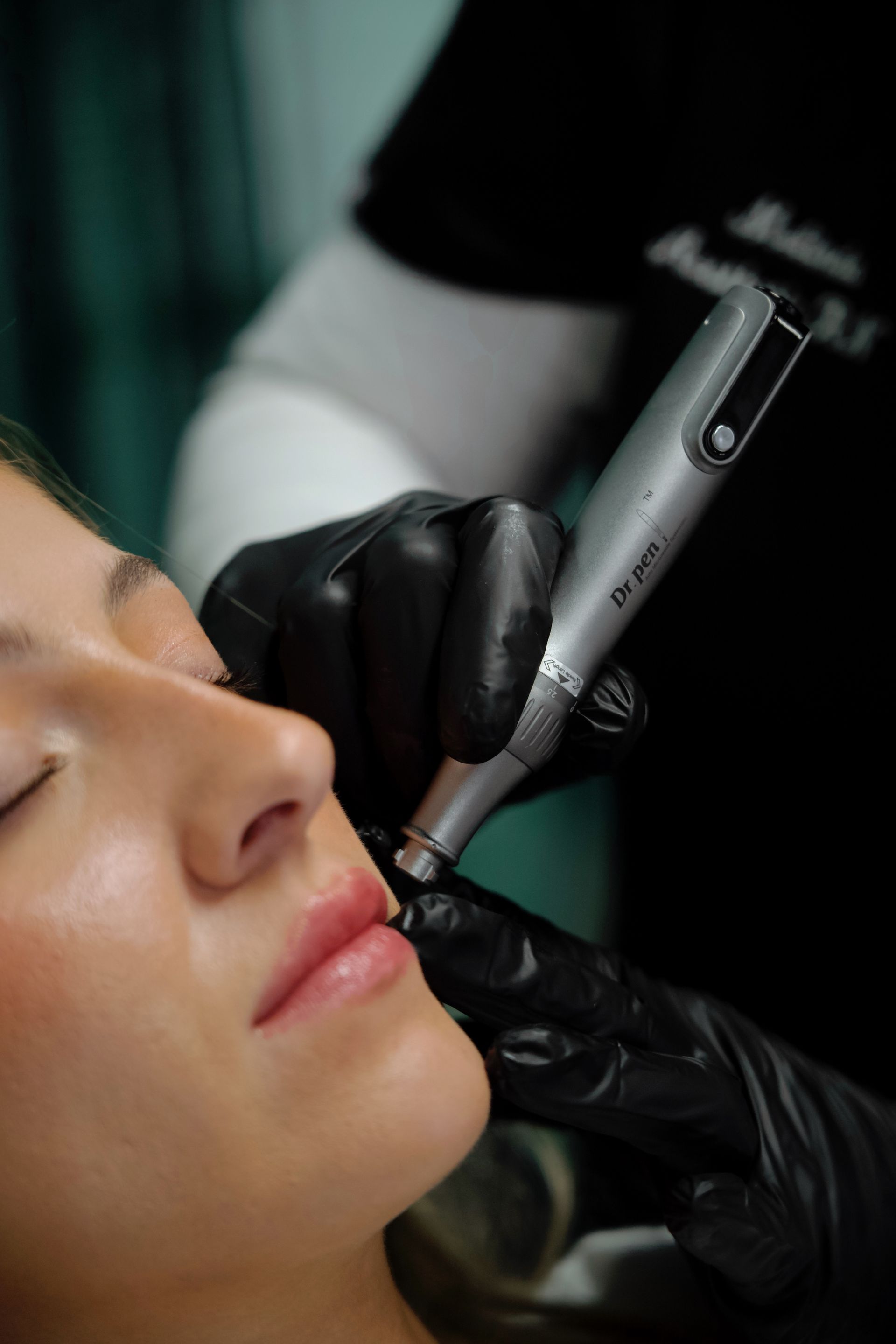 A person receiving lip micropigmentation. A technician uses a device on their lips in a beauty setting.