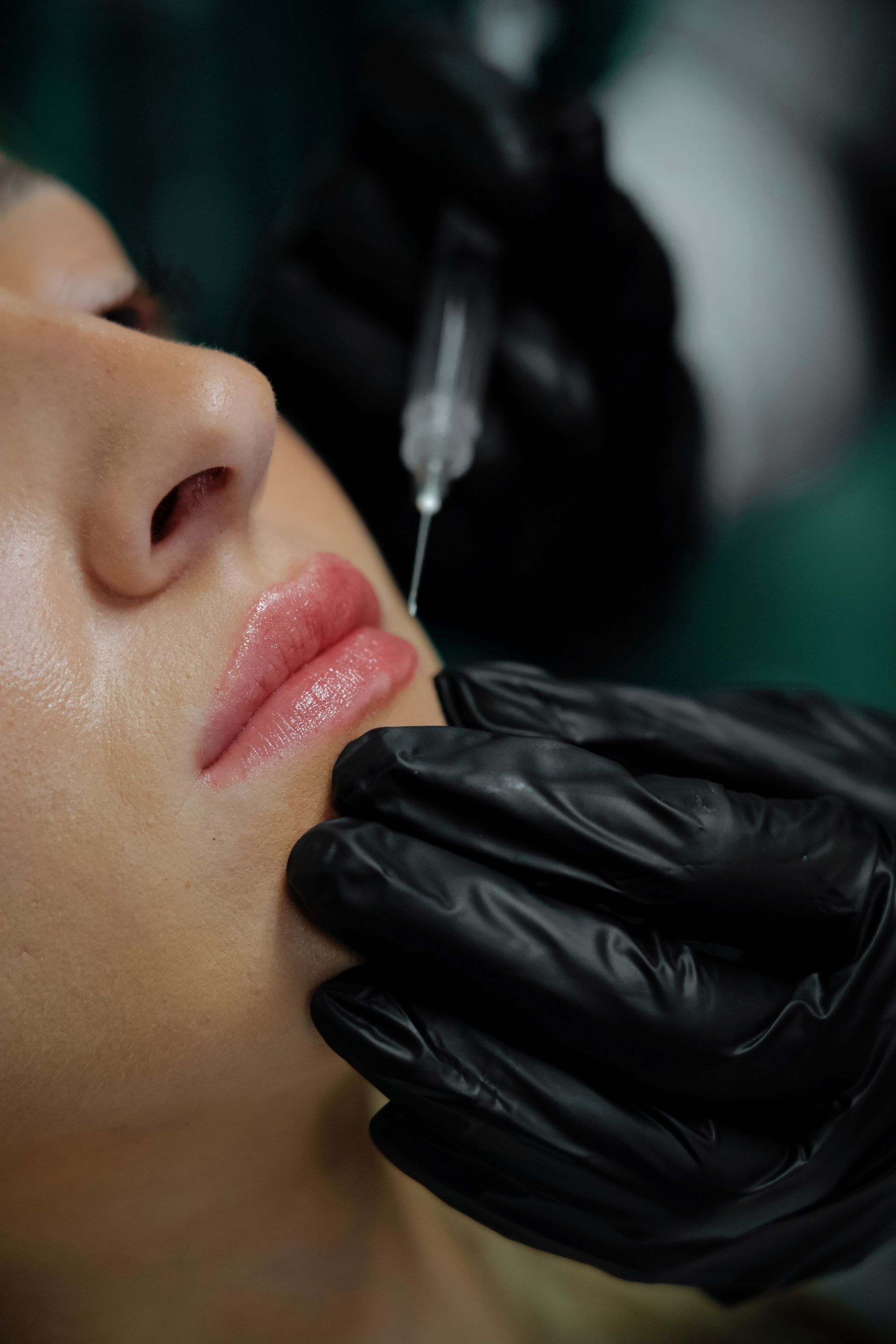 A woman is getting a botox injection in her lips.