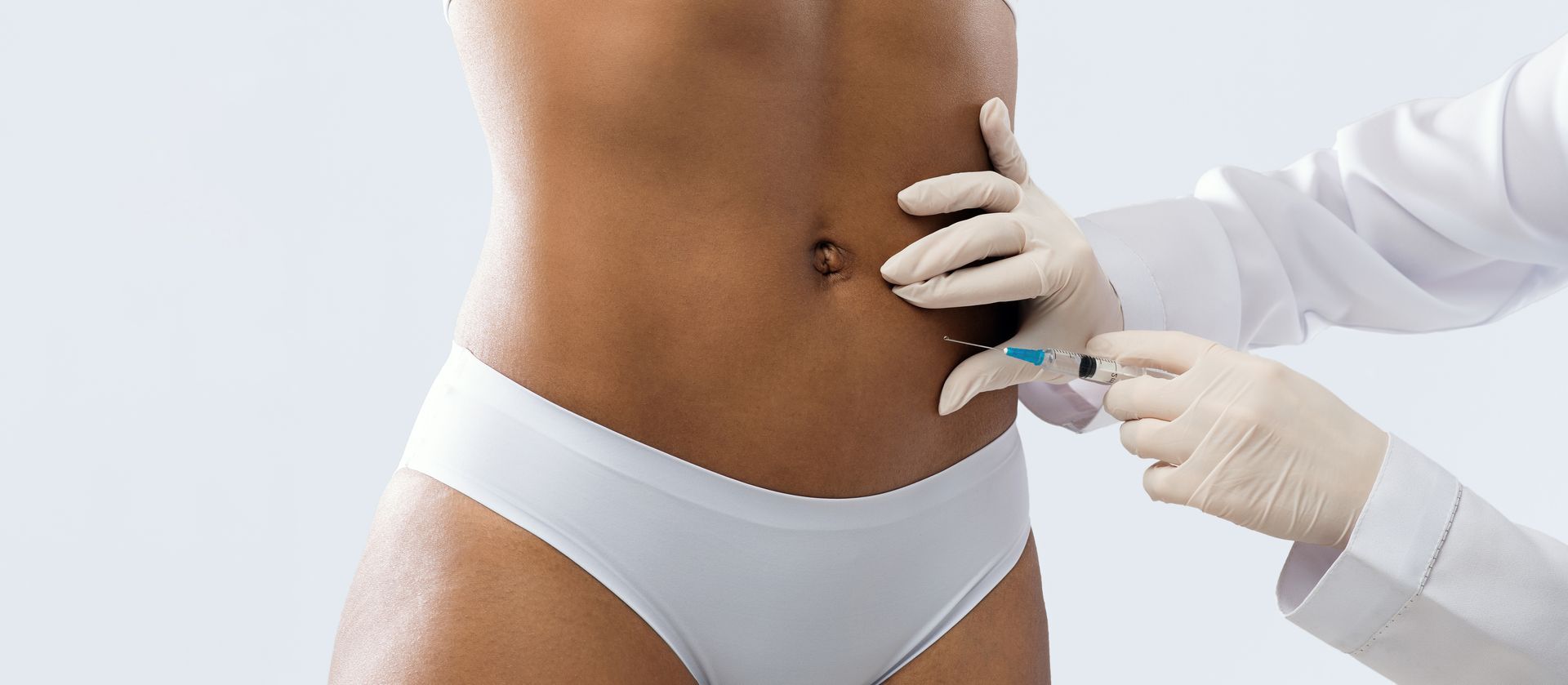 A woman is getting an injection in her stomach.