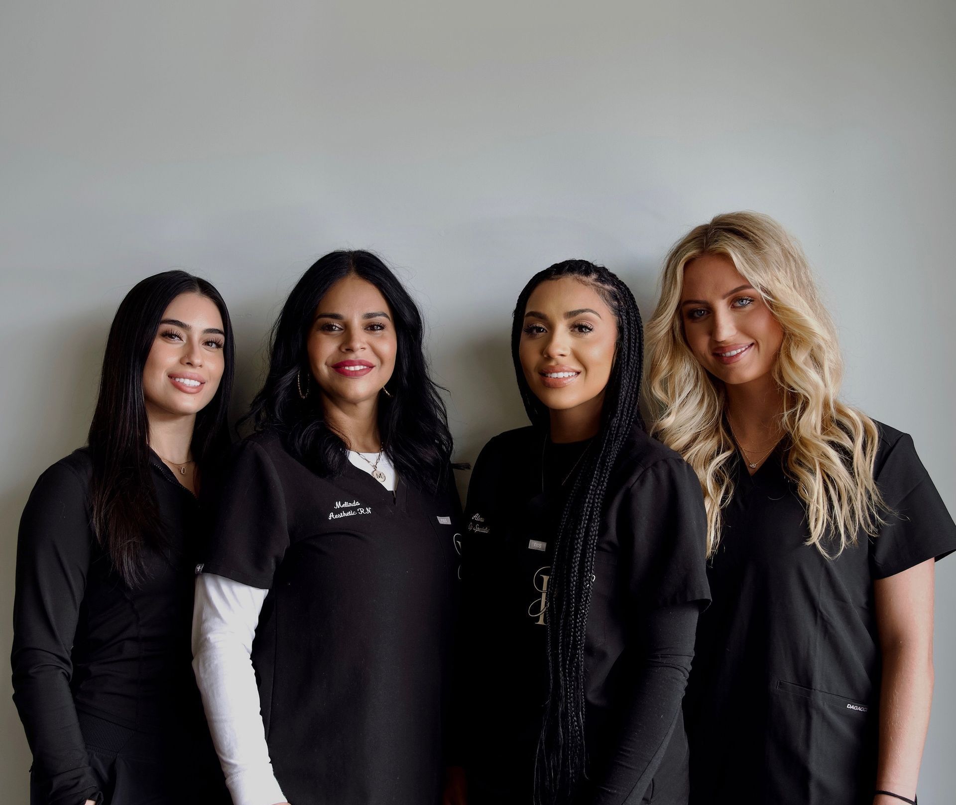 A group of four women in scrubs are posing for a picture.