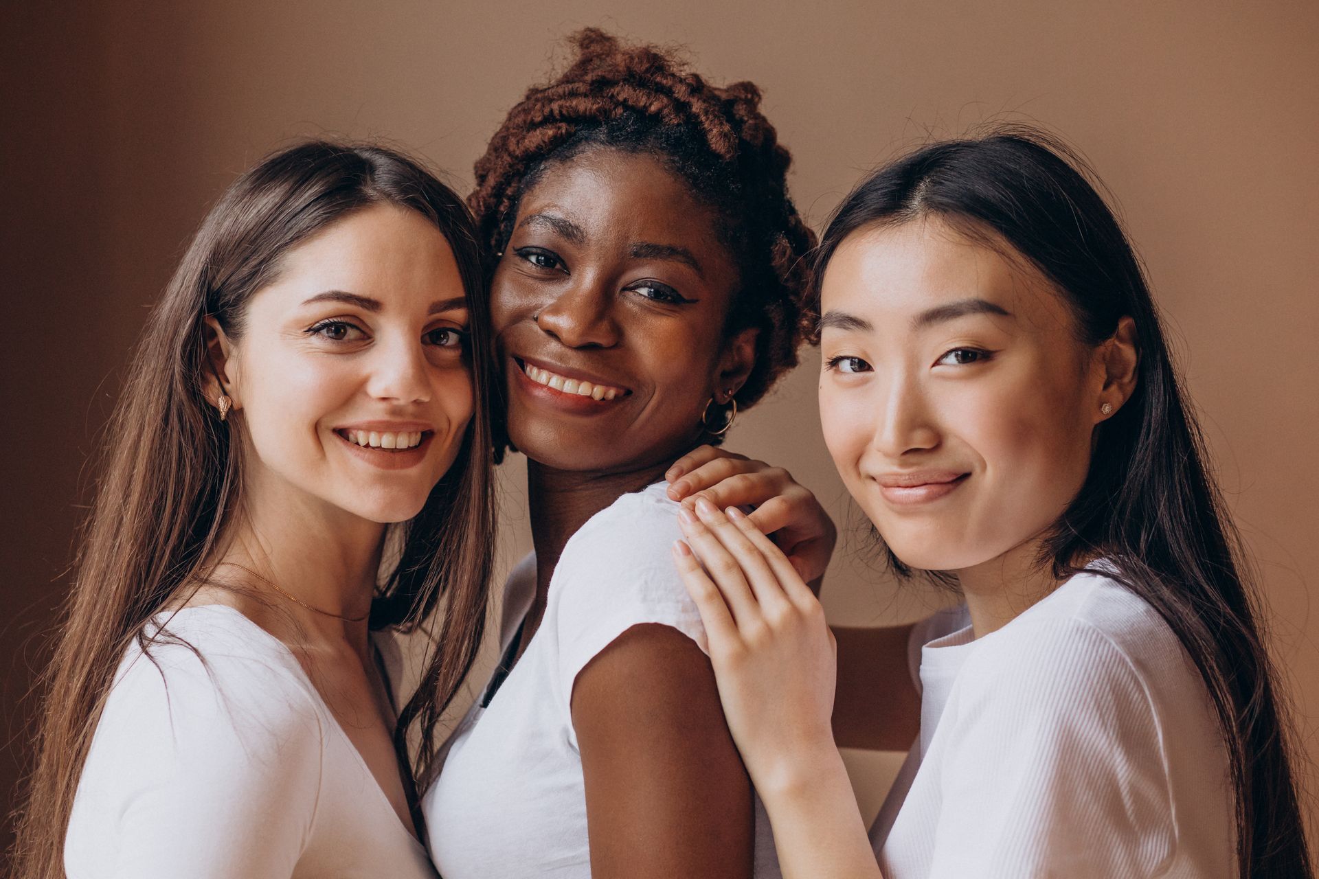 Three women of different races are posing for a picture together.