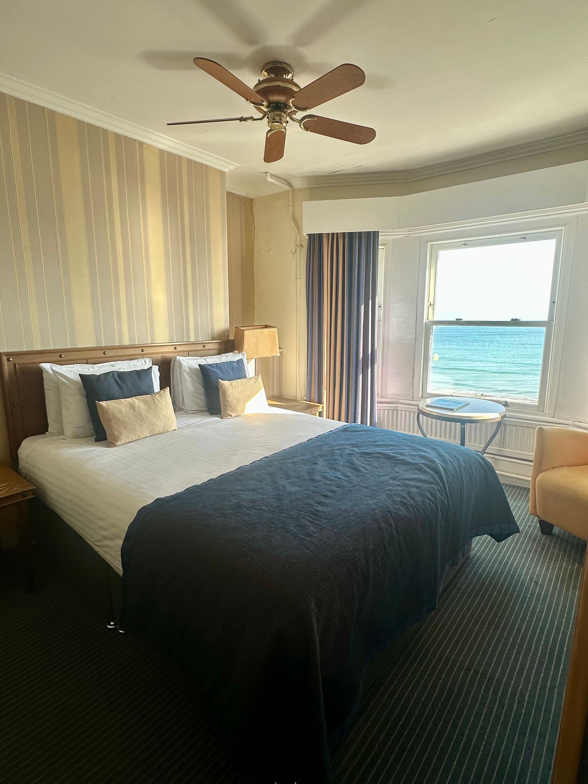 A hotel room with a large bed and a ceiling fan.