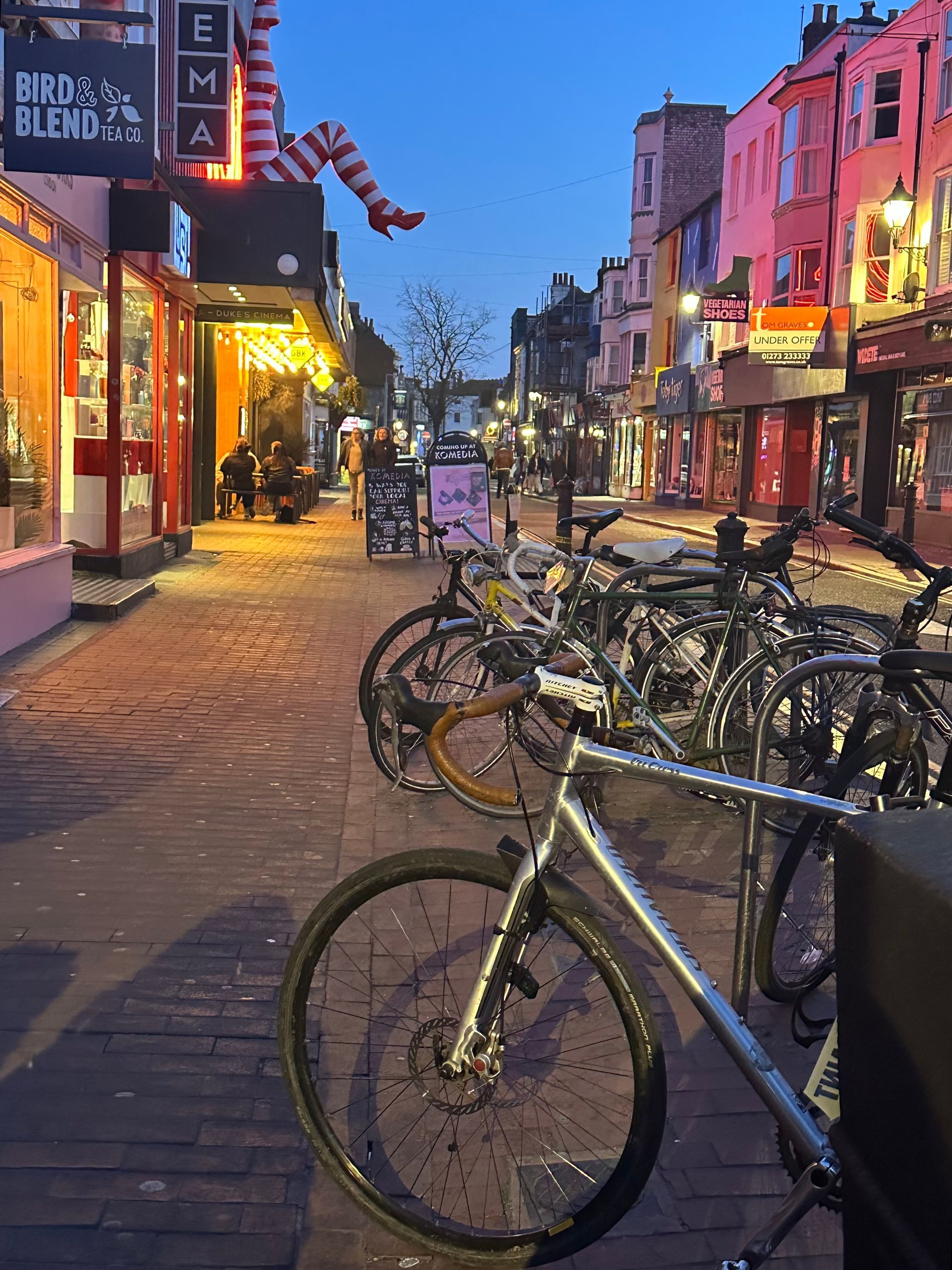 A bicycle is parked on the sidewalk in front of a store that says ema