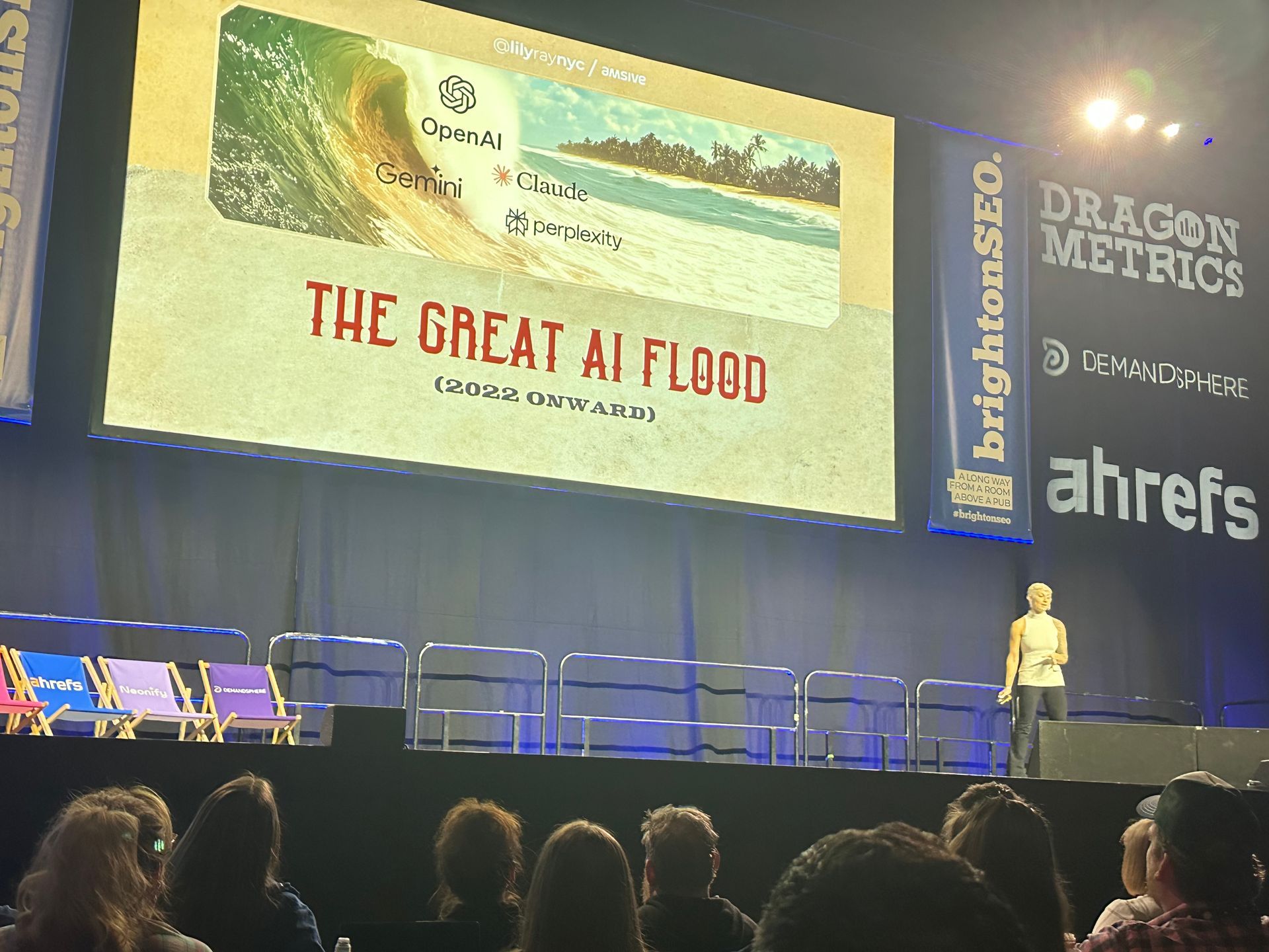 A group of people are sitting in front of a large screen that says the great ai flood
