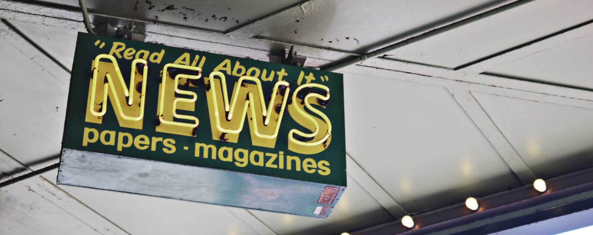 picture with neon news sign hanging from roof