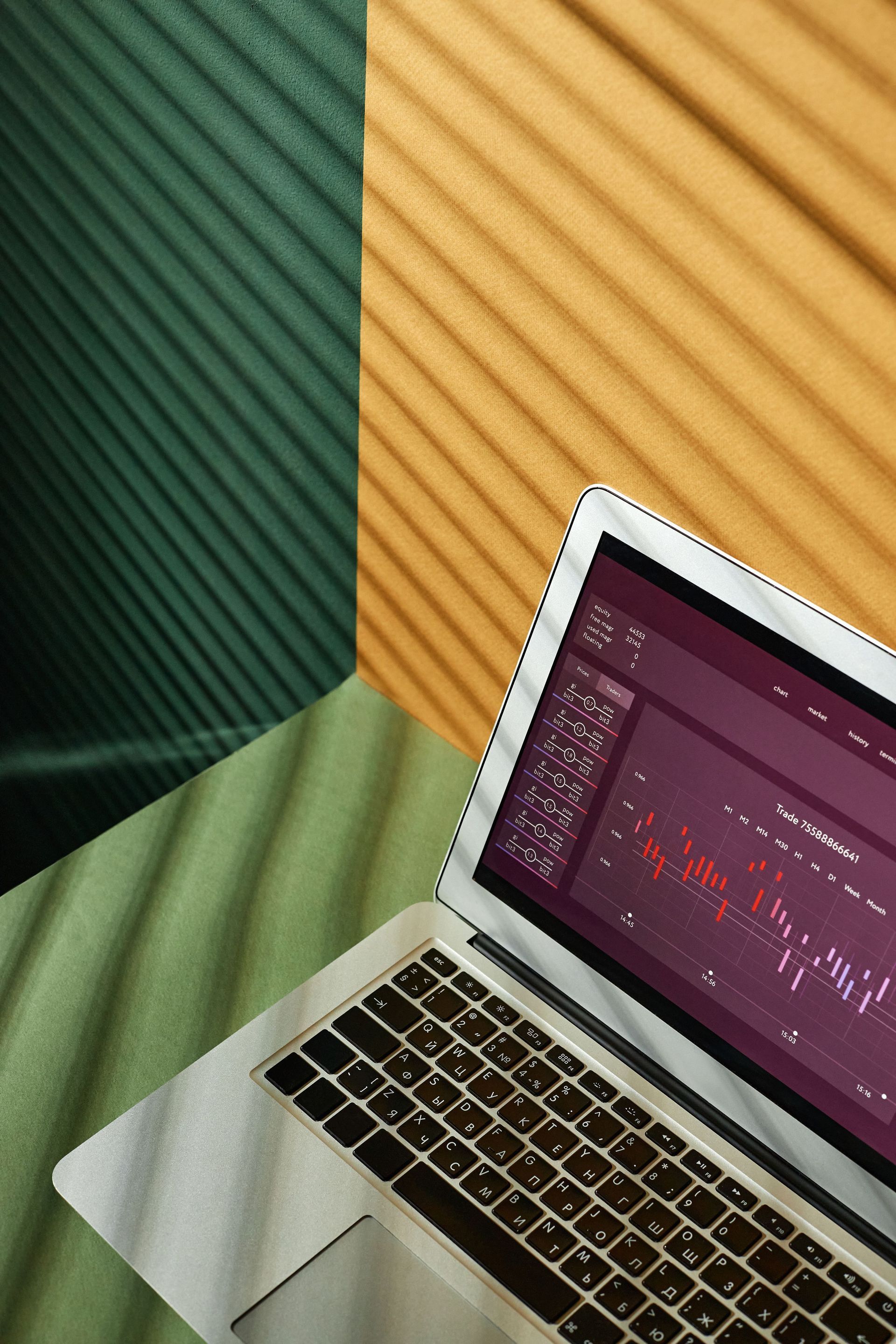 Laptop on a table beside green and orange striped fabric panels