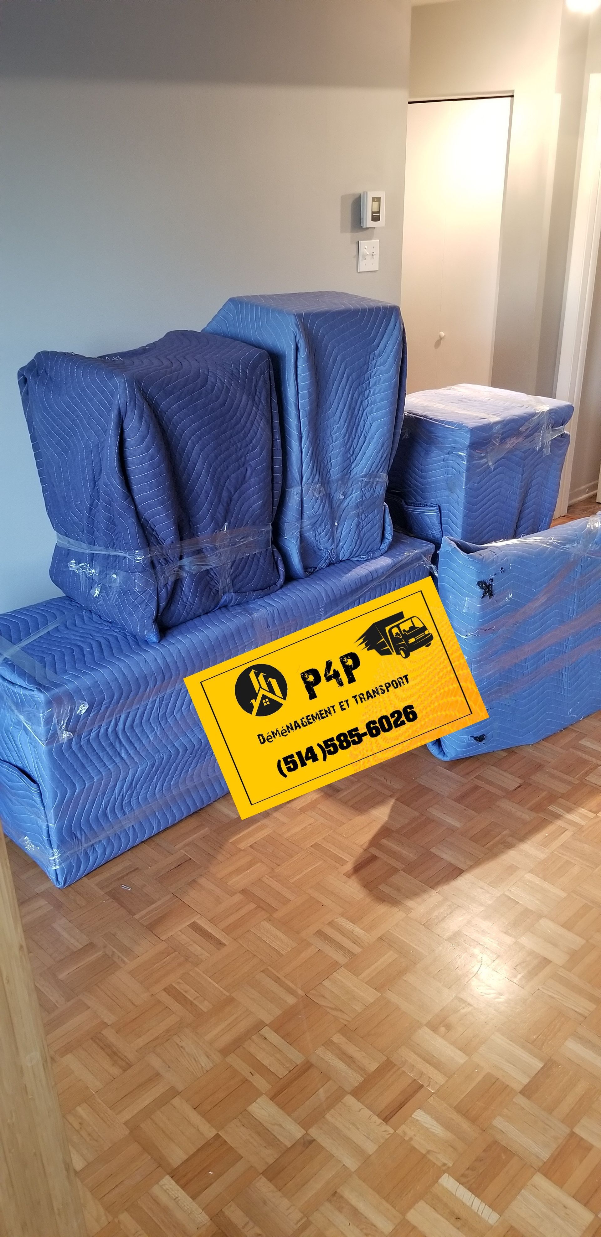 Un salon rempli de boîtes emballées dans du plastique bleu et d'un panneau.