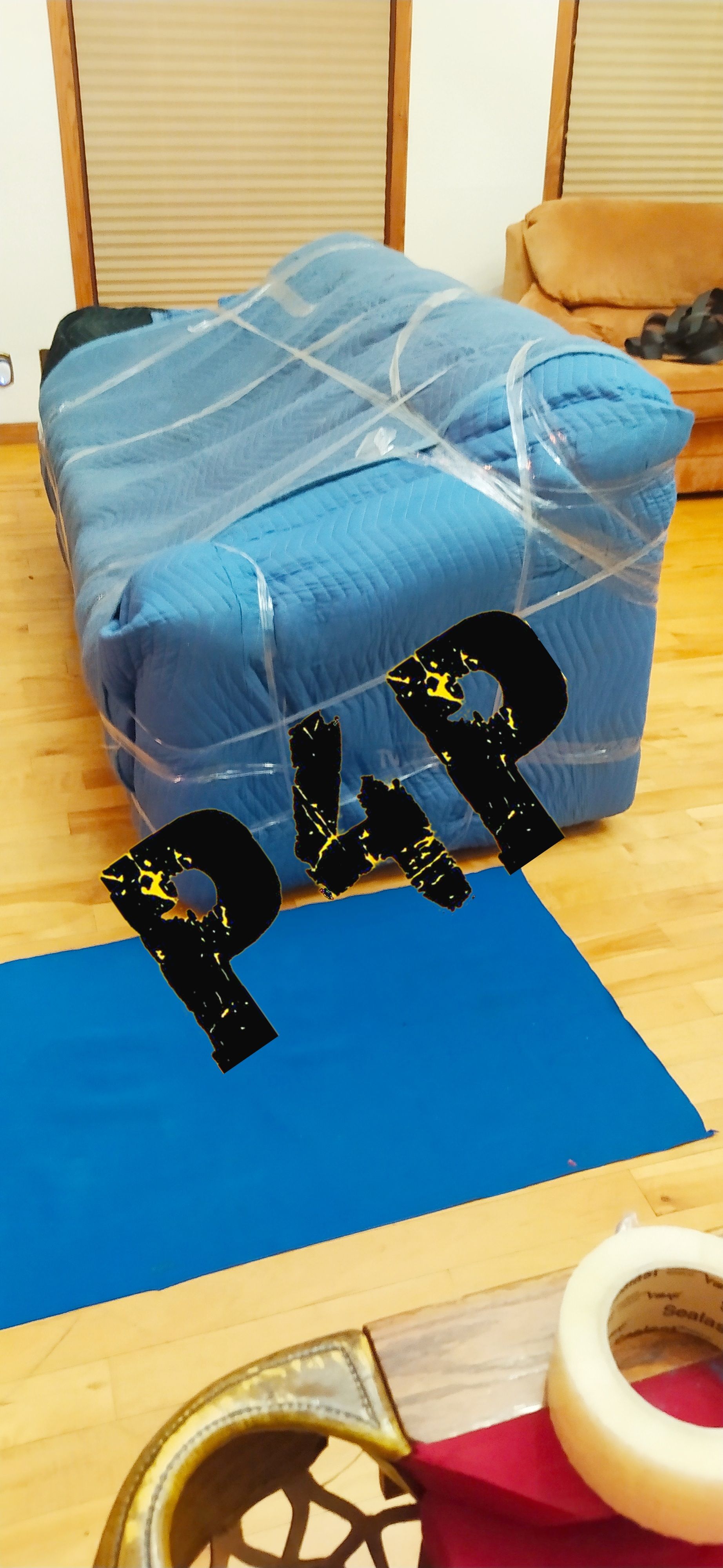 Un canapé bleu est enveloppé dans une pellicule plastique dans un salon.