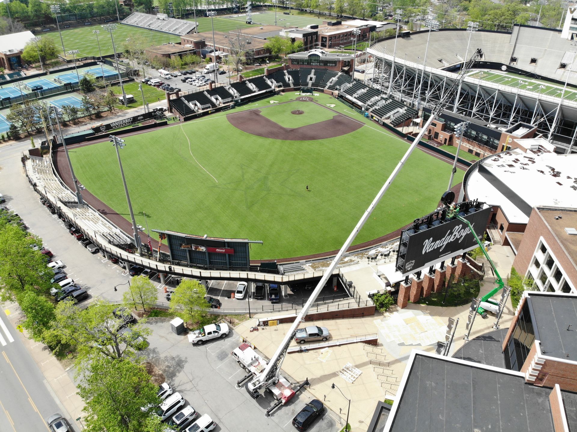 Aerial view of a baseball stadium with a green field, black seating, and construction equipment.