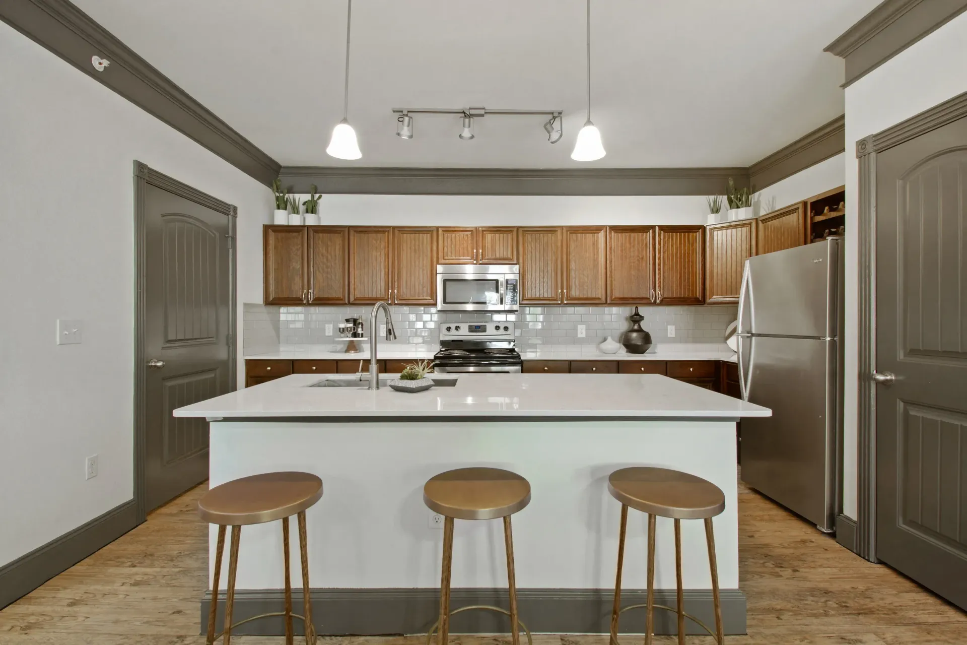Modern kitchen with island, wood cabinets, stainless steel appliances, and stools.