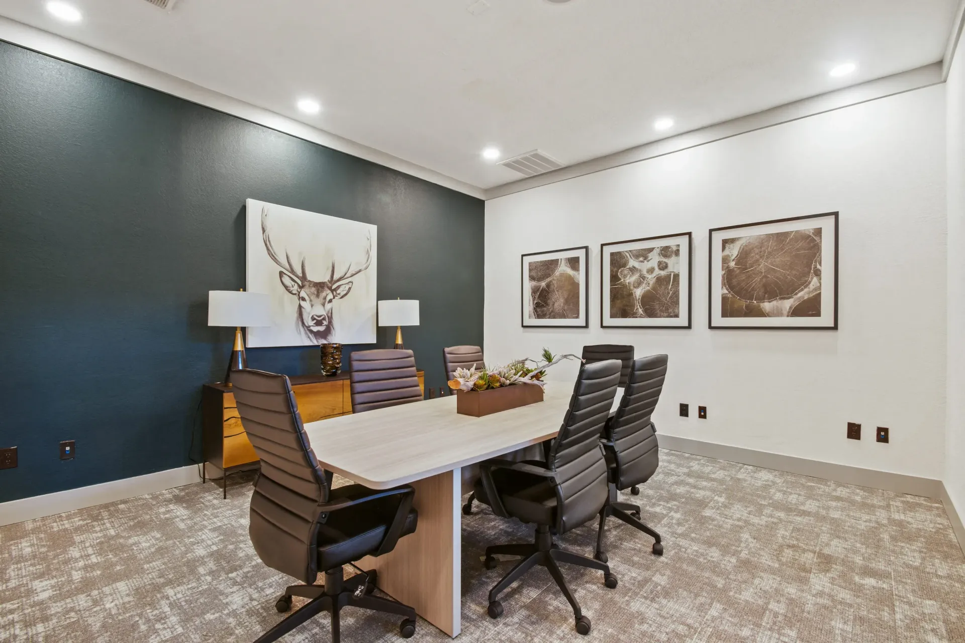 Modern kitchen with island, three mounted TVs, stone archway, and wood accents.