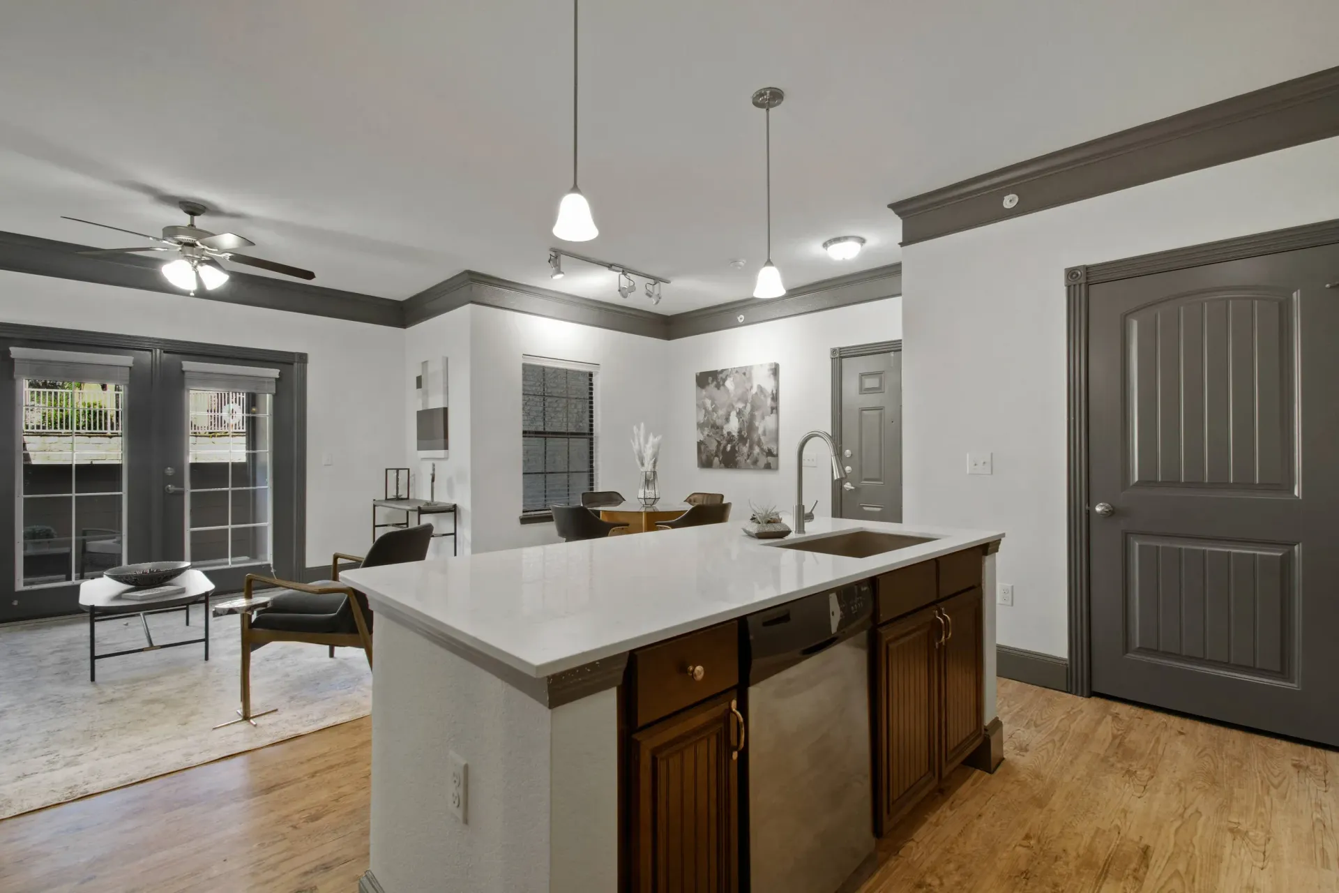 Carport with three bays. Two have garage doors. Beige walls, gravel driveway, blue sky.