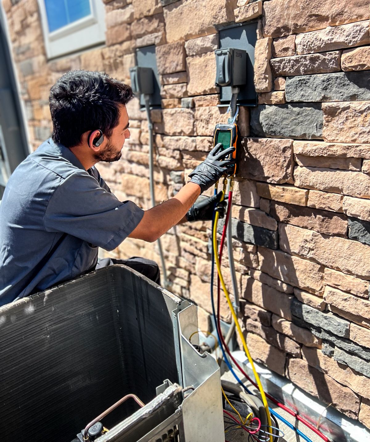 A man is working on an air conditioner outside of a brick building.