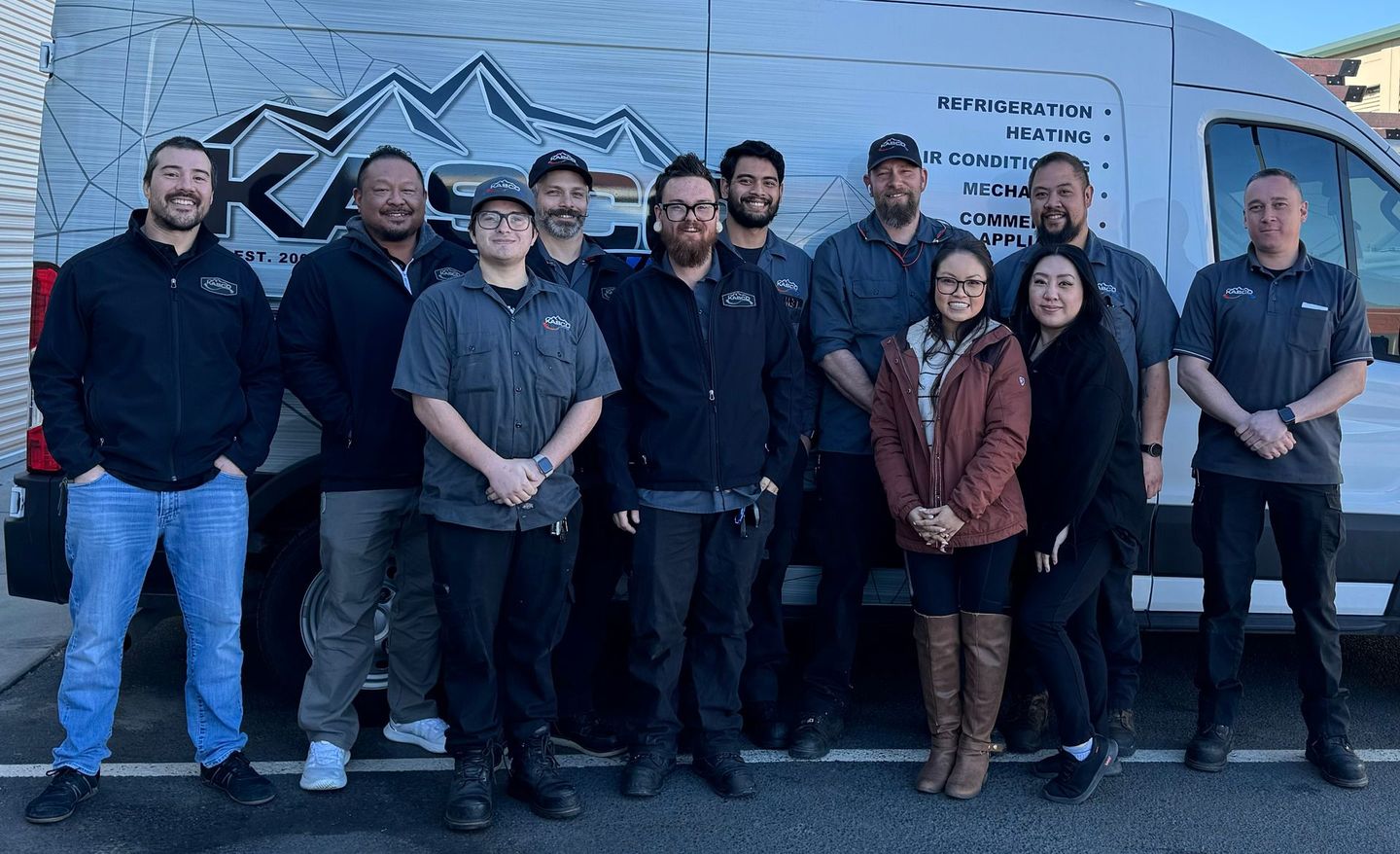 A group of people are posing for a picture in front of a van.