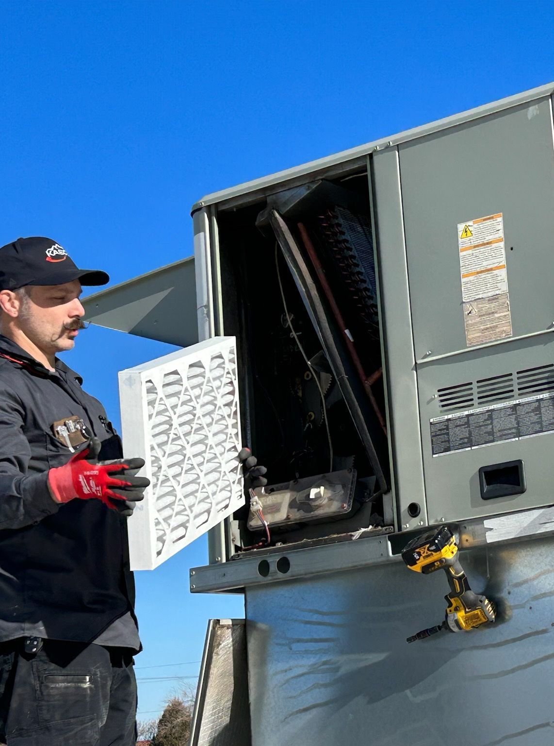 A man is holding a piece of paper in front of an air conditioner.