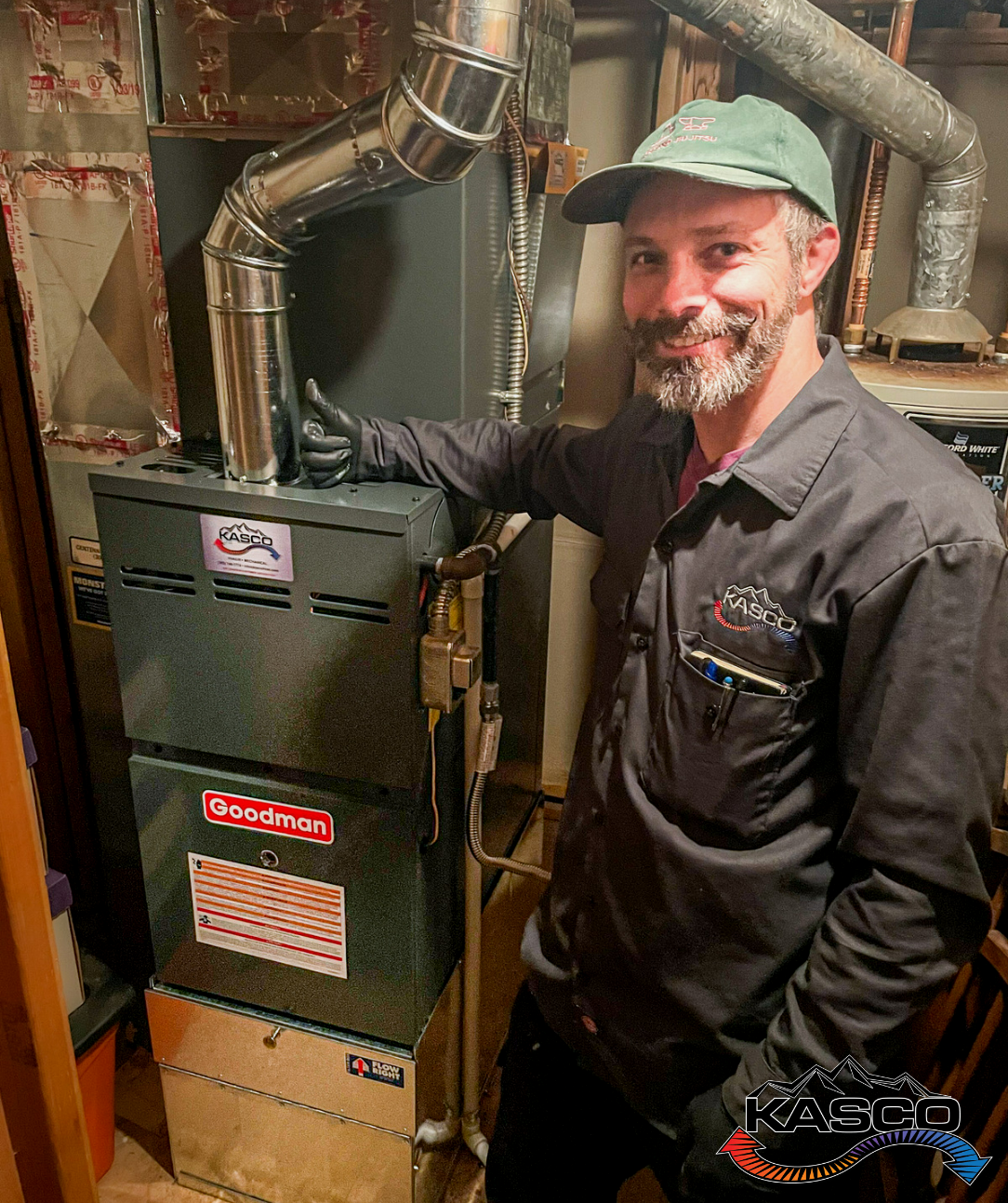 A man is standing next to an air conditioner in a basement.