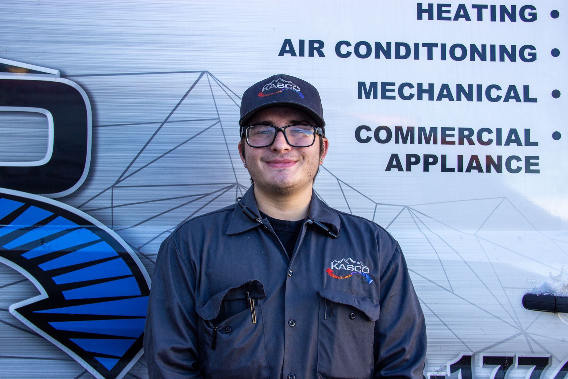 A man wearing a hat and glasses is standing in front of a sign that says heating air conditioning mechanical commercial appliance