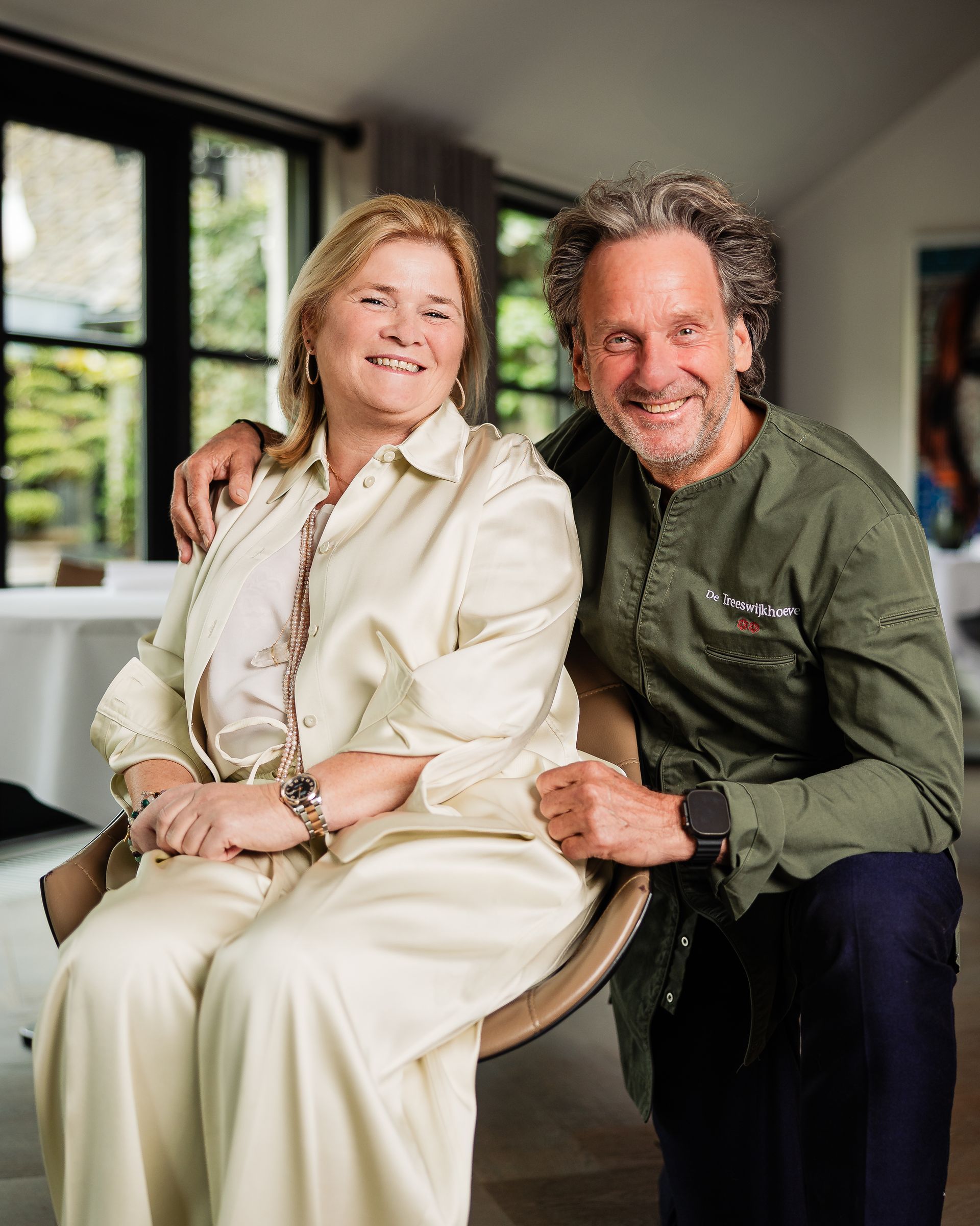 Een chef-kok gebruikt een pincet om garnering op een wit bord te schikken in een schemerig verlicht restaurant.