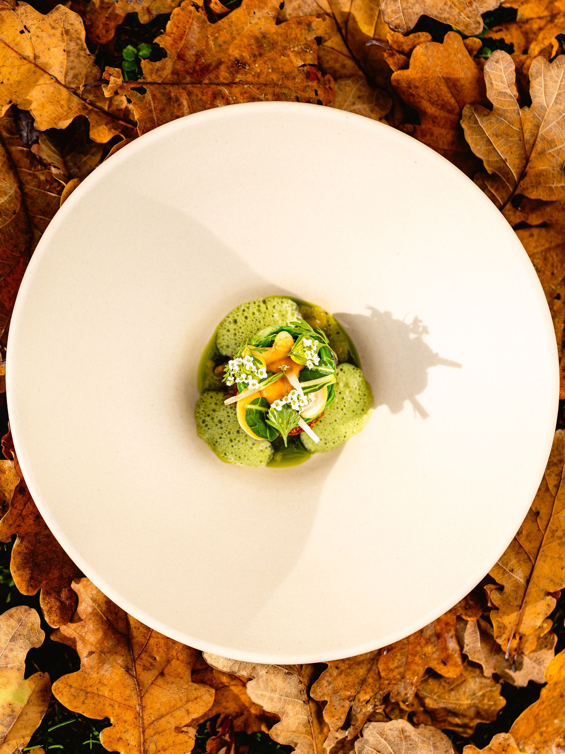 Close-up van twee pizza's op een tafel, waarvan er één wordt gesneden. Ook kaarsen en borden zijn aanwezig. Bij L'Essenza Rotterdam.