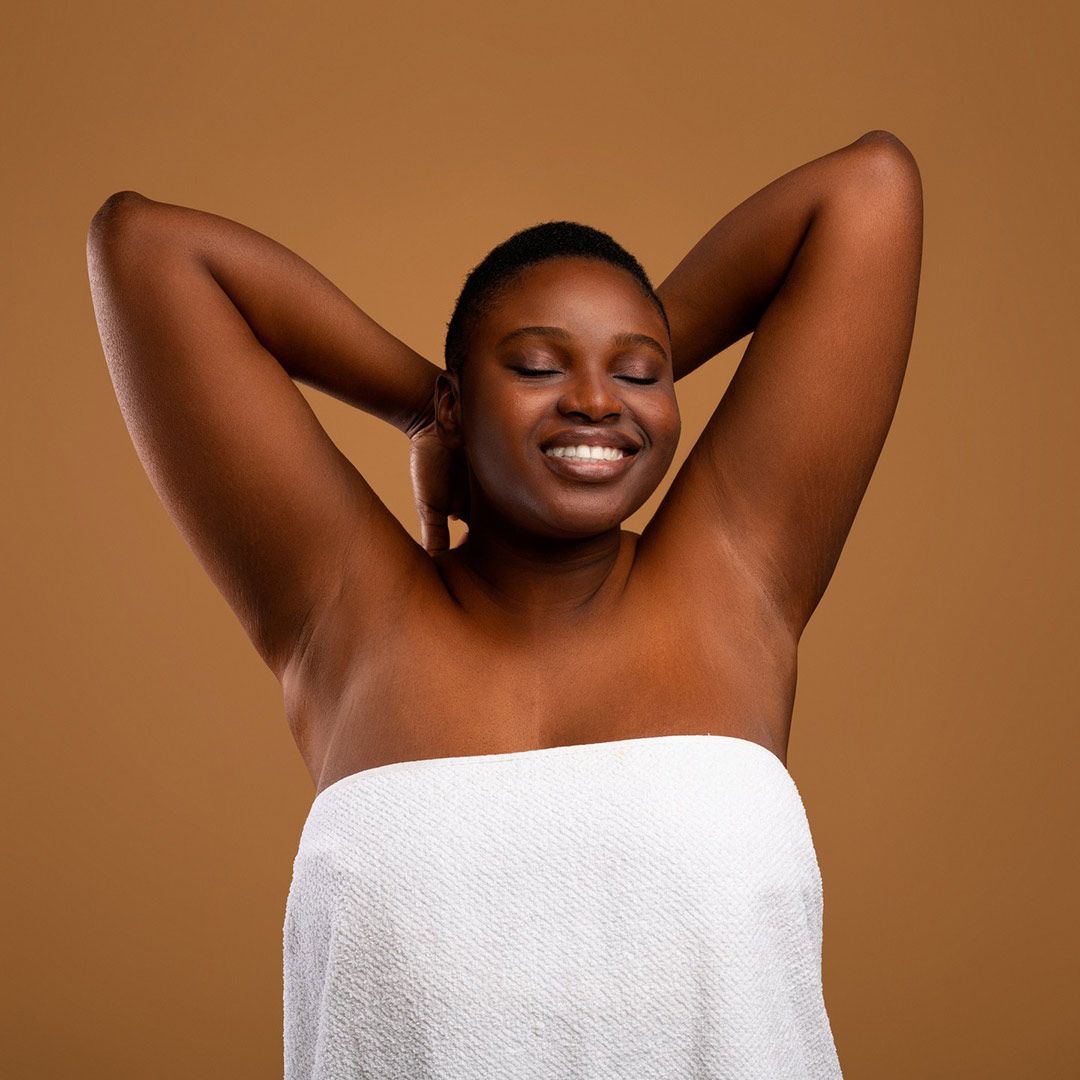 A Woman Is Wrapped In A White Towel And Smiling — Chez Belle Skin Care & Beauty Centre in Pimlico, QLD