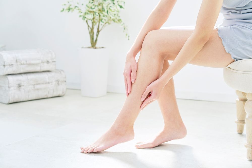A Woman Is Holding A Flower Between Her Feet Next To Candles — Chez Belle Skin Care & Beauty Centre in Pimlico, QLD