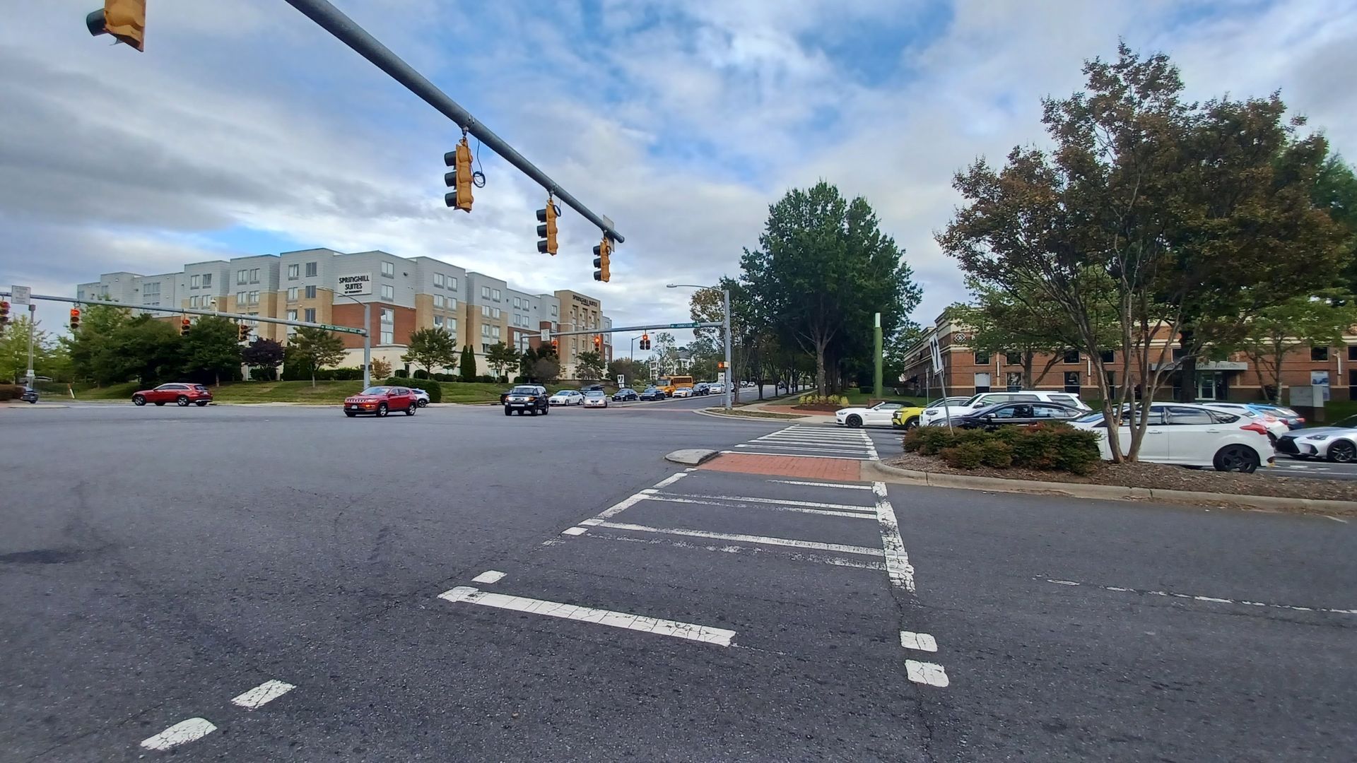 Intersection with traffic lights and crosswalk, cars, and buildings on a cloudy day in Cotswold, Charlotte.