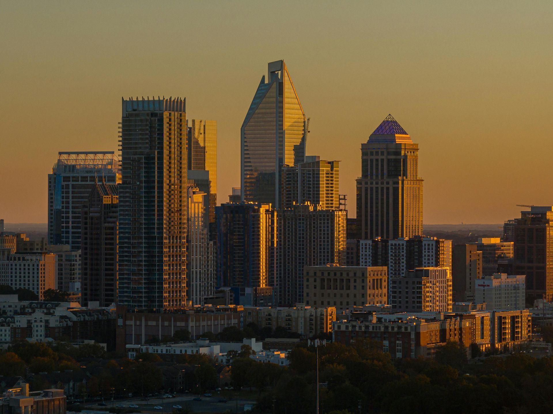 Uptown, Charlotte, North Carolina skyline at sunset with gold and orange hues.