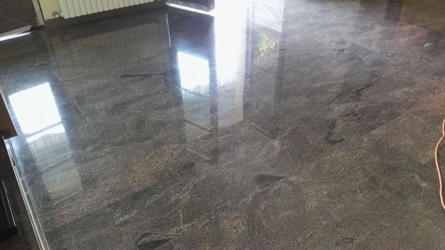 Piano di lavoro in granito scuro lucido e levigato che riflette la luce, in una cucina.