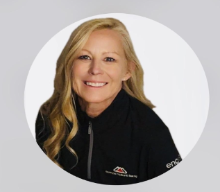 Smiling woman in a black zip-up jacket against a light gray background