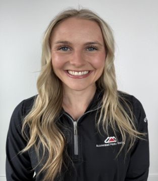 Smiling person in a black zip-up jacket against a light background