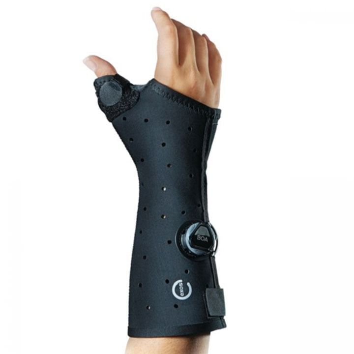 Black wrist brace with thumb support and dial strap on a hand, isolated on white background