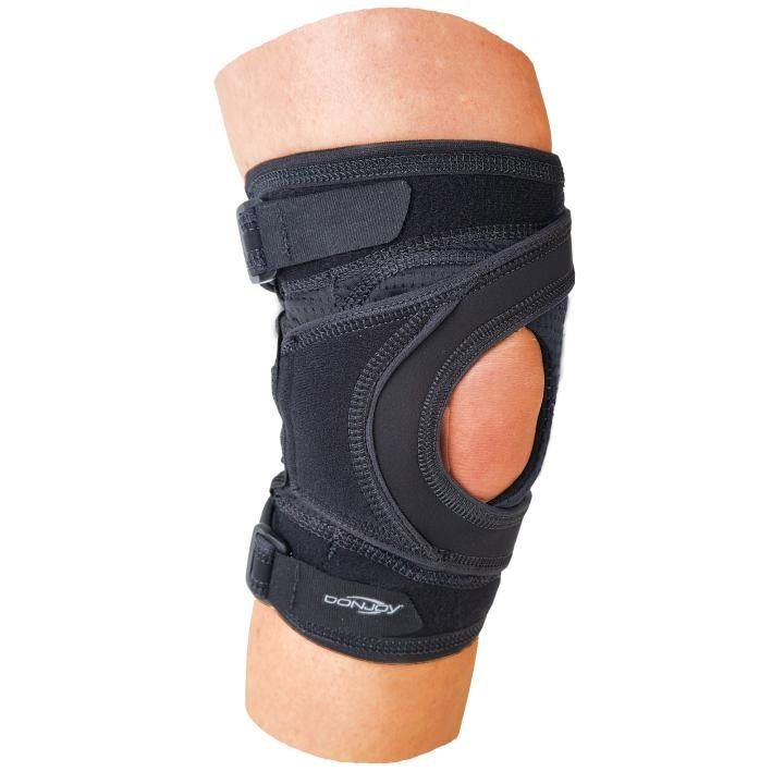 Black knee brace with side cutout on a bent leg, isolated on white background