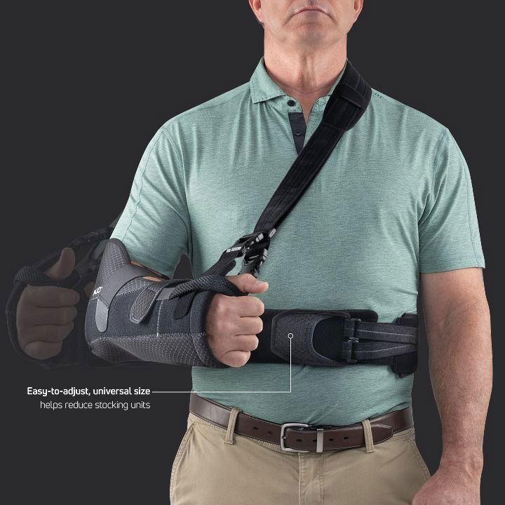 Person wearing a black shoulder-and-arm brace with a waist strap over a green shirt