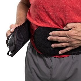 Person adjusting a black waist support belt over a red shirt and gray pants