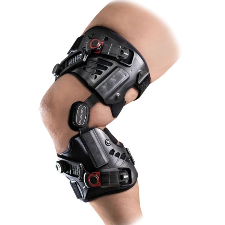 Black orthopedic knee brace with straps on a bent leg