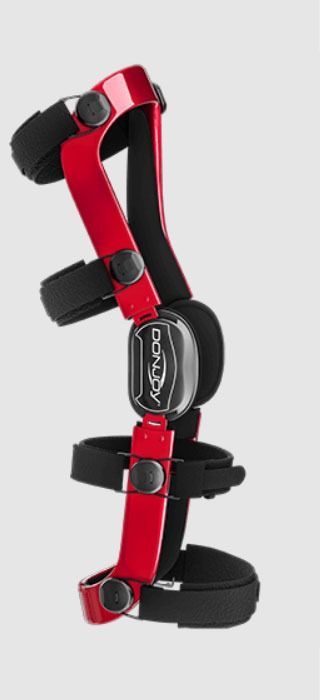 Red and black adjustable orthopedic knee brace with straps and metal hinges on a white background