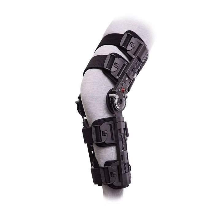 Black adjustable knee brace with metal hinges on a gray leg model.
