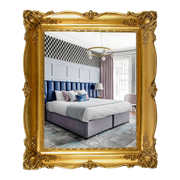 Bedroom interior reflected in a gold ornate frame; features a bed, headboard, patterned wallpaper, and curtains.