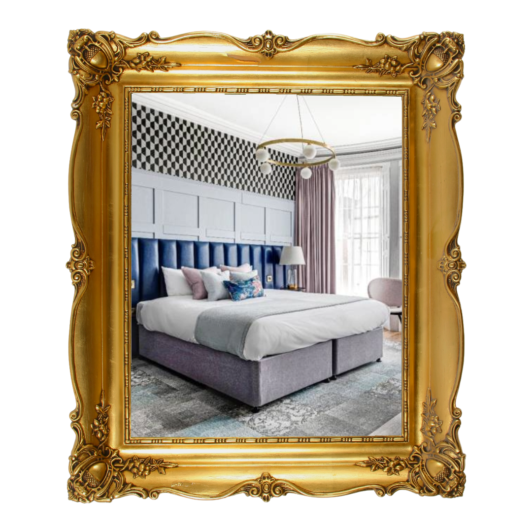 Bedroom interior reflected in a gold ornate frame; features a bed, headboard, patterned wallpaper, and curtains.