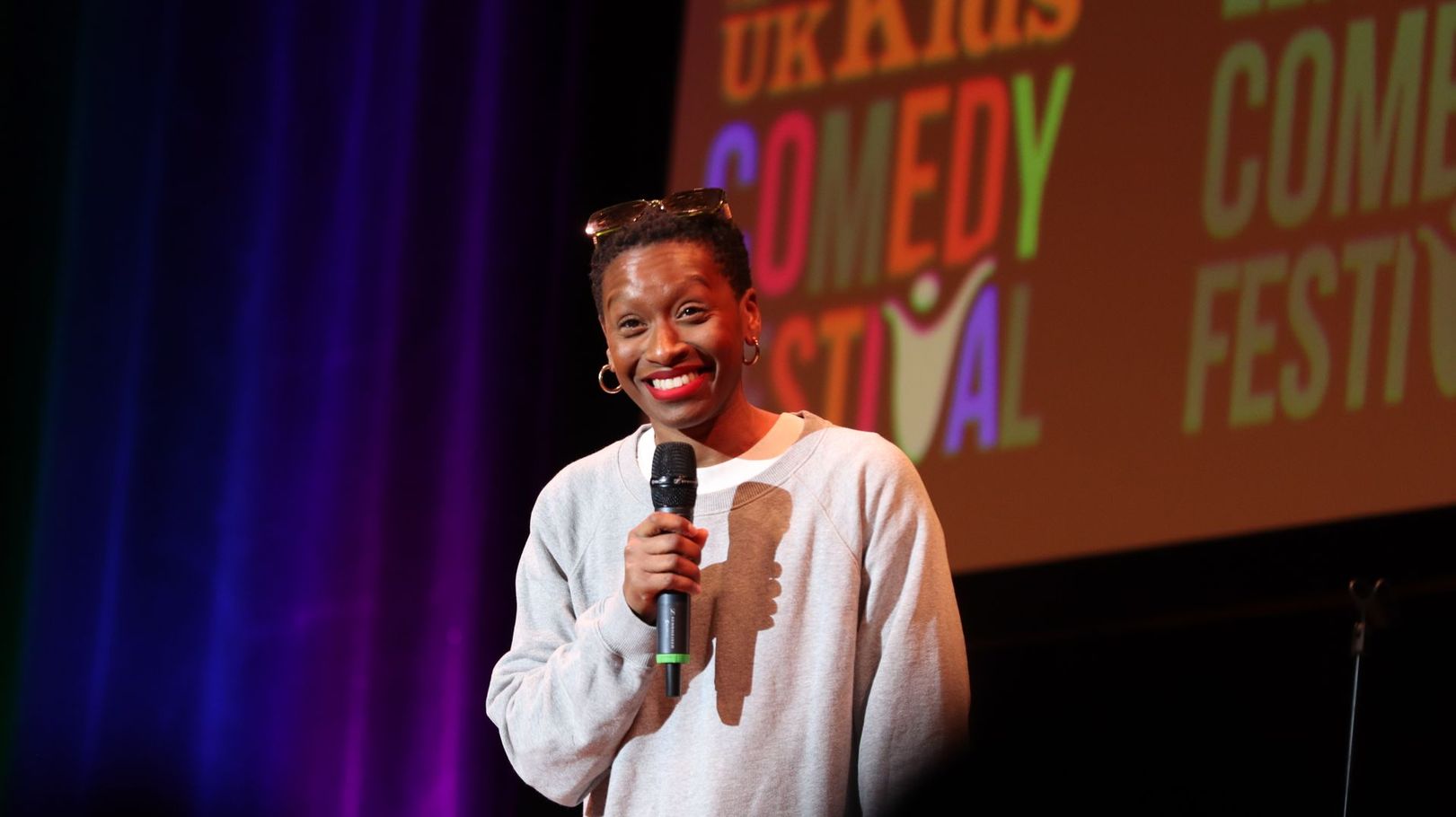 Man in blue suit, smiling, looking upward against a teal background.