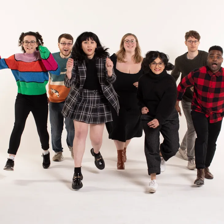 Group of eight people running forward, looking surprised, against a white background.