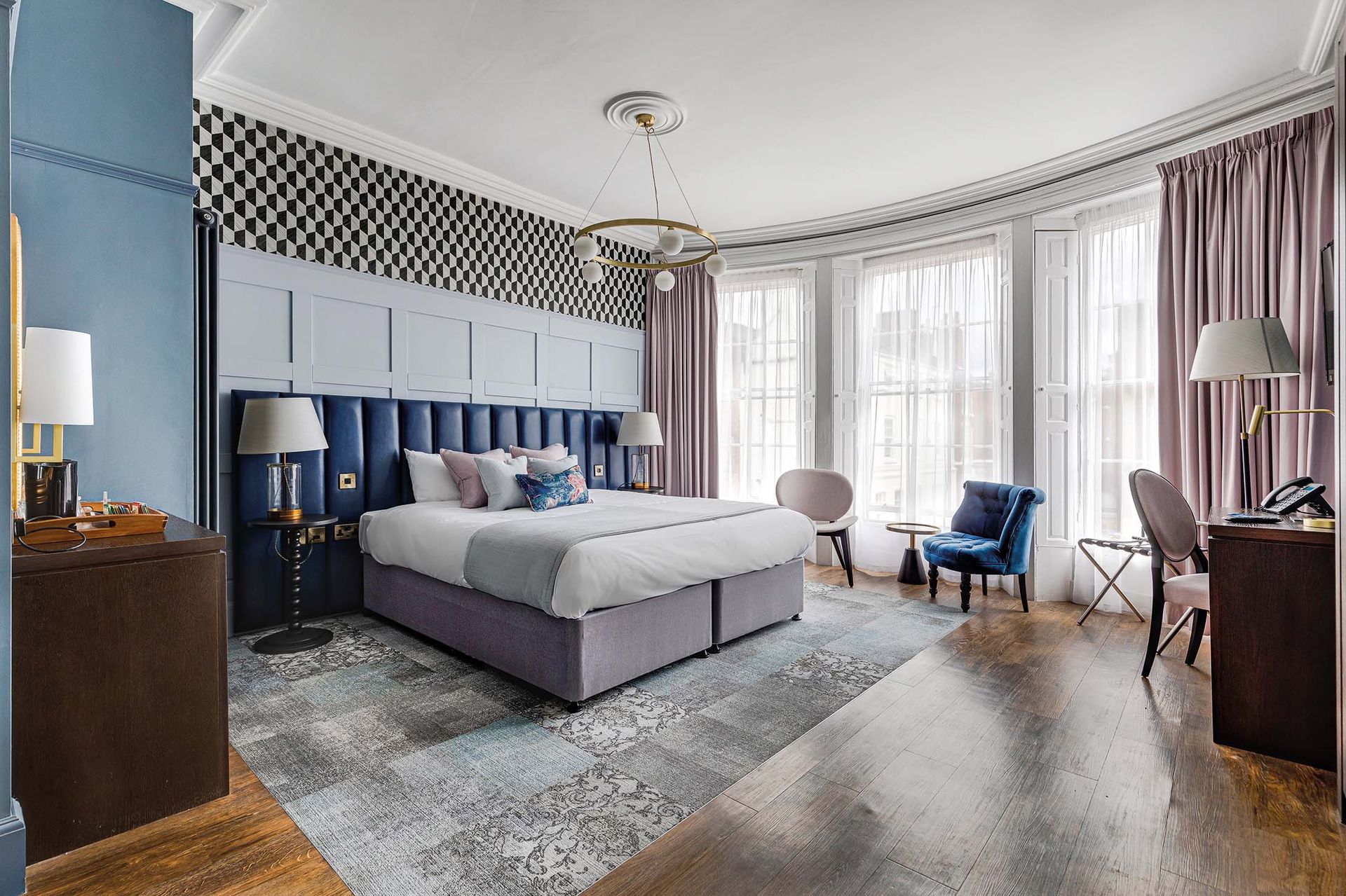 Elegant hotel bedroom with a large bed, bay window, and ornate decor.