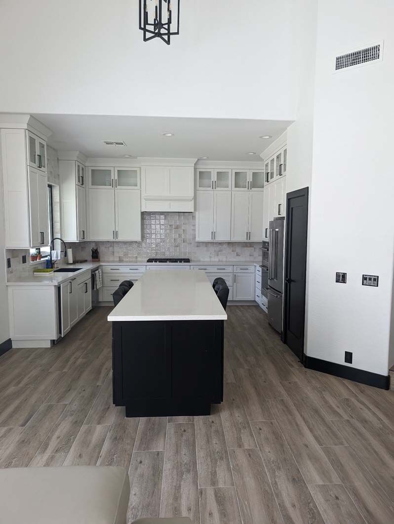 A kitchen with white cabinets and a large island in the middle.