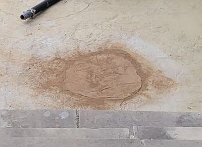 A concrete floor with a hole in it and a hose next to it.