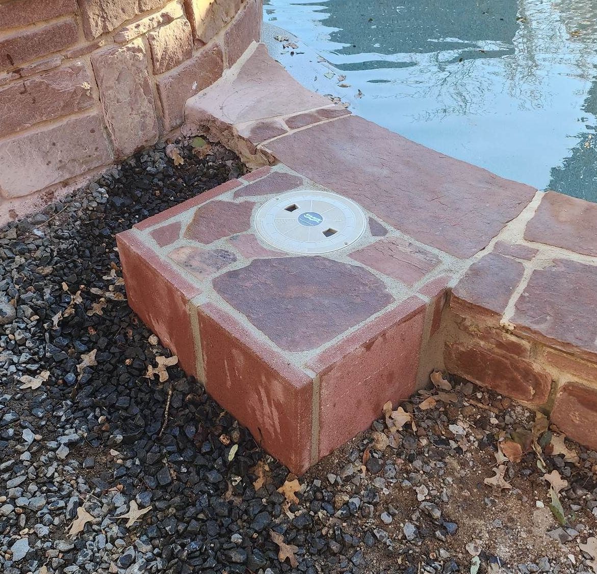 A brick block is sitting next to a swimming pool