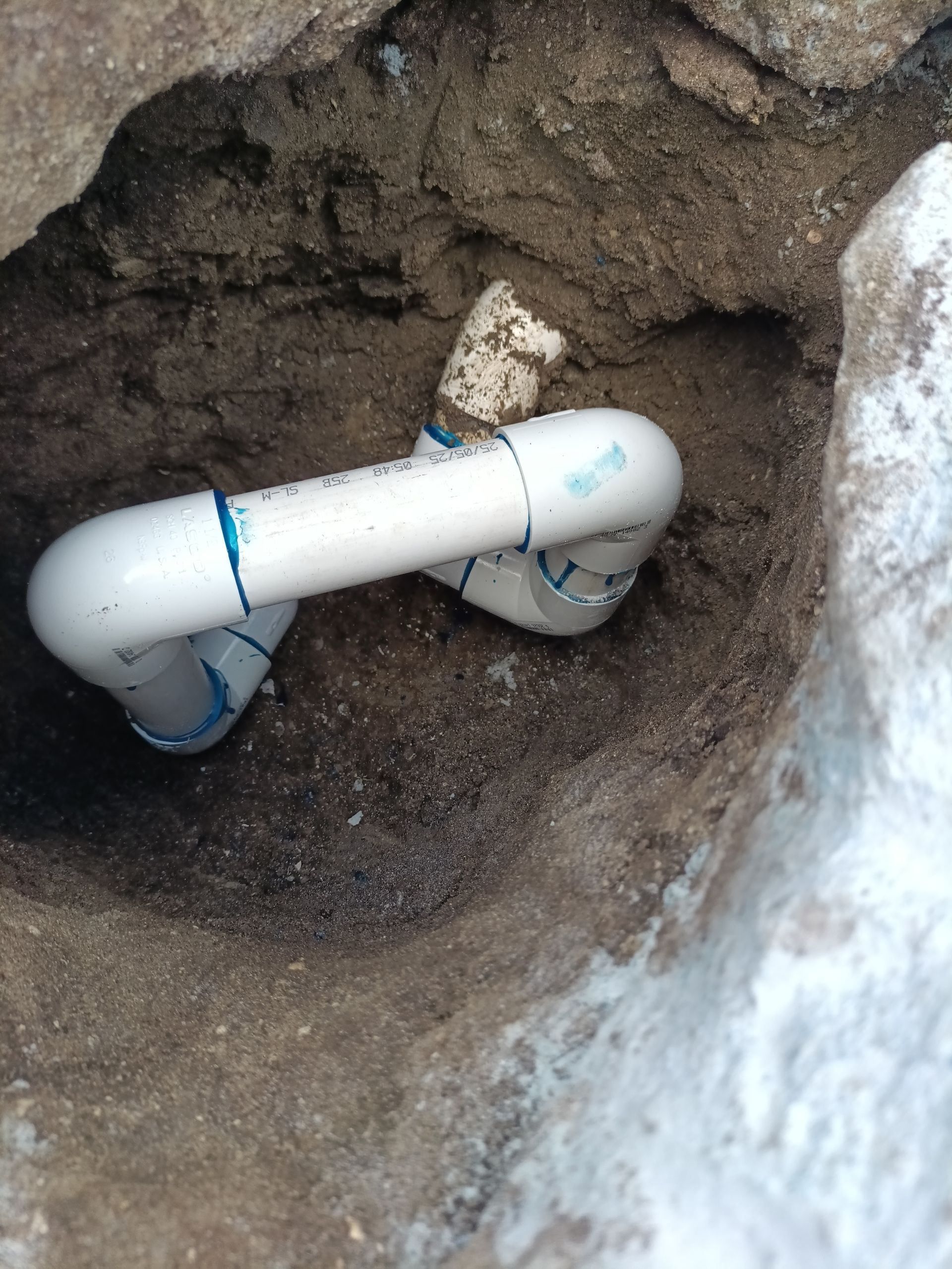 White PVC pipes plumbed in a hartford loop going into the back side of a pool wall