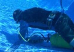 A scuba diver is swimming underwater in a pool.