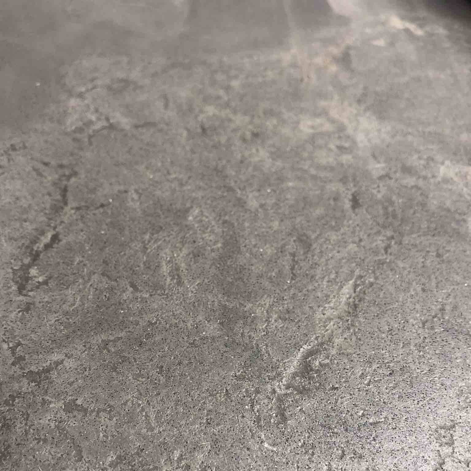 a close up of a gray rock finish concrete counter top .