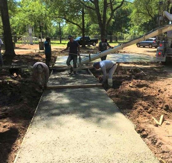 Construction workers pouring concrete for a sidewalk at an outdoor site in Houston, TX.